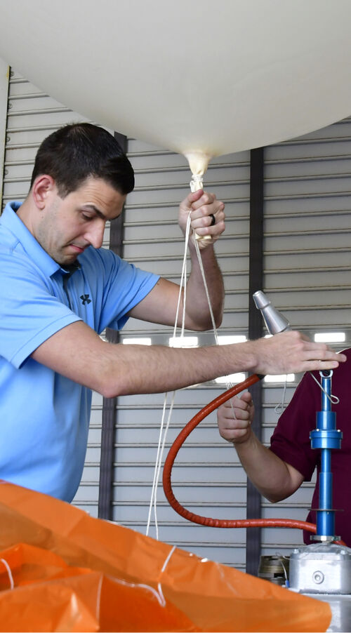 A person from the National Weather Service is working to ready a weather balloon for launch.